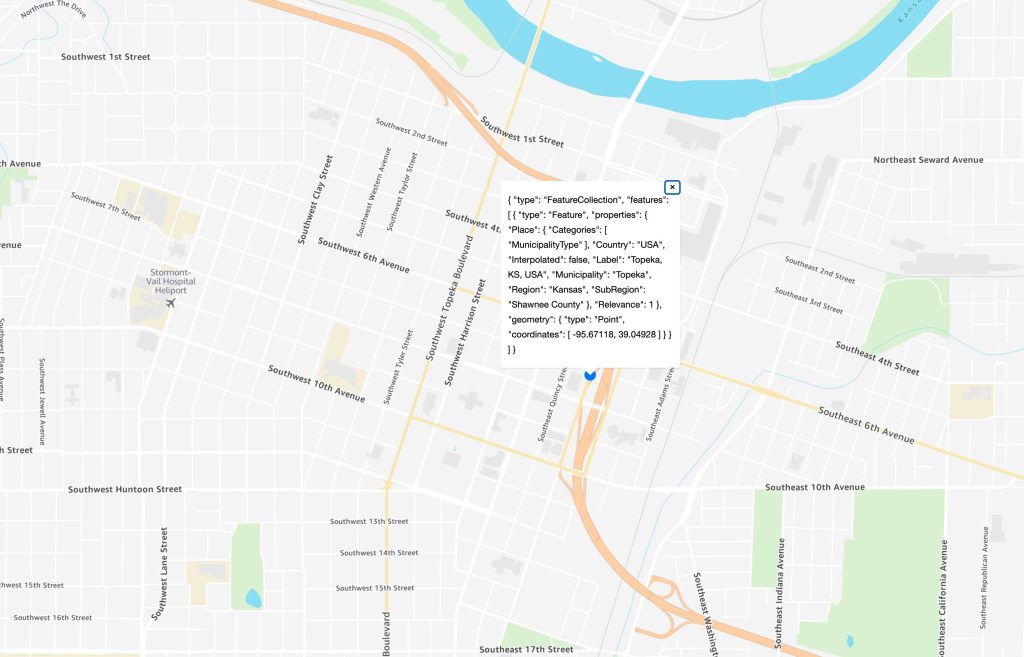 Image showing a map with a pin for our search result, with a geojson in a pop up window representing the results of our Amazon Location Service search result.