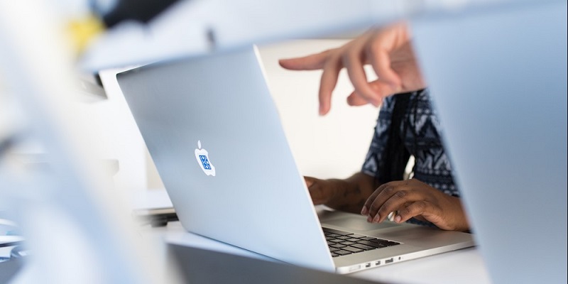 Photo of the hands of two people at a laptop