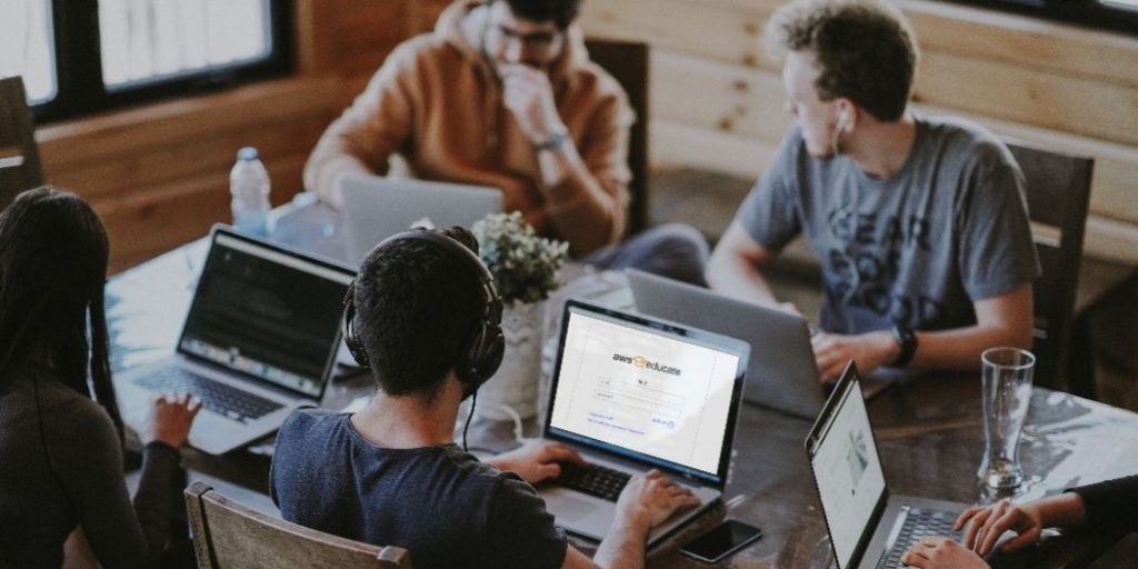 team of individuals at a startup collaborate over laptops at table