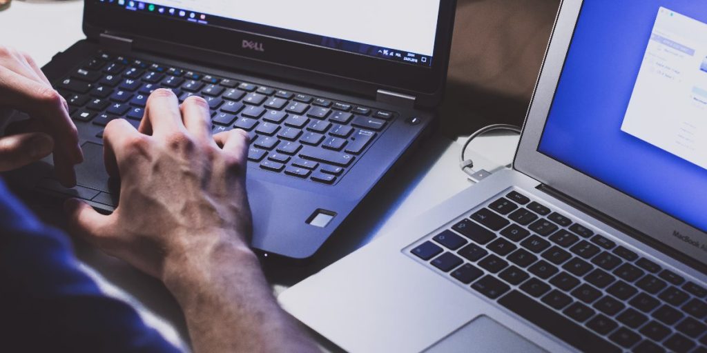 man working between two laptops