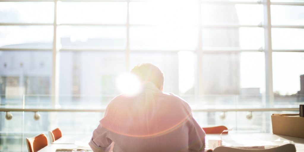 man with back to camera in office with sun coming through windows