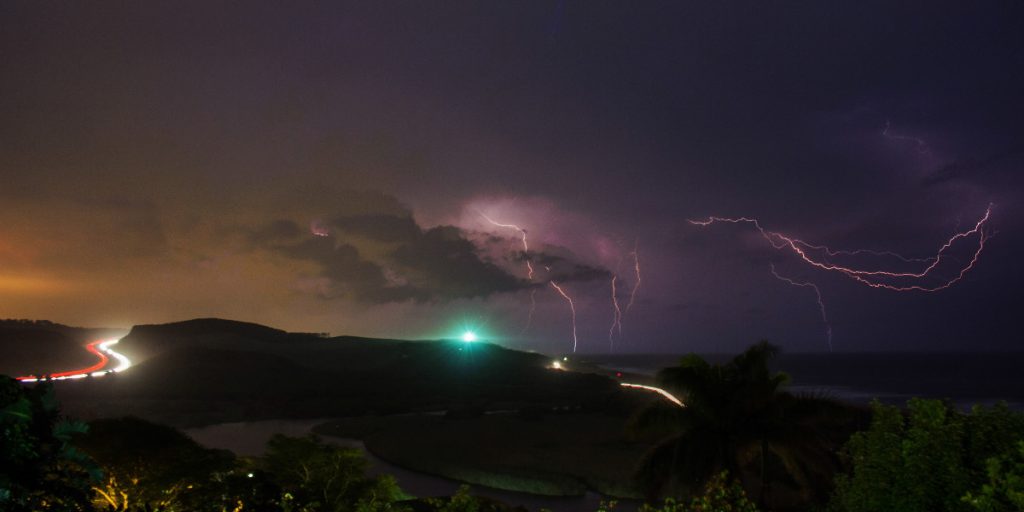 lightning strike at night over mountains with highway