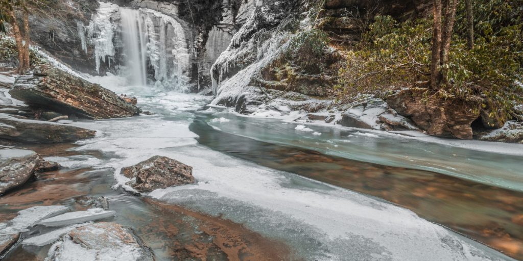 frozen river with waterfall in woods