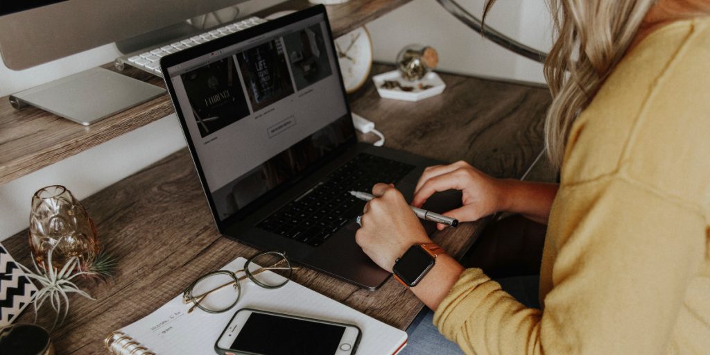 woman working on her laptop at home next to phone and notebook