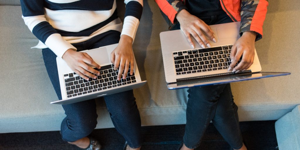 Aerial shot of two women on their laptops on a couch; Photo by Christina @ wocintechchat.com on Unsplash