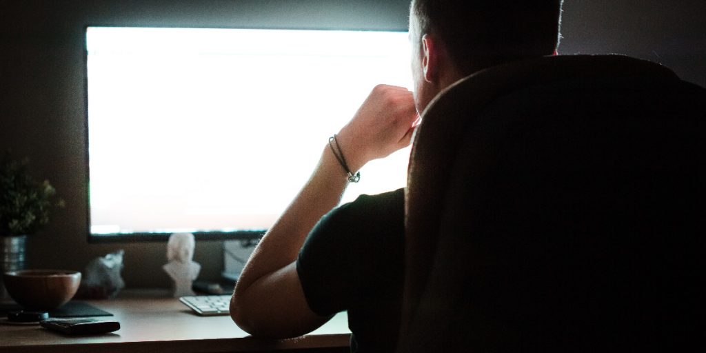 man working at desktop computer at night shadow