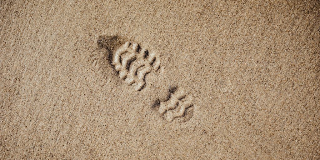 bootprint in sand; photo by Bernard Hermant via Unsplash