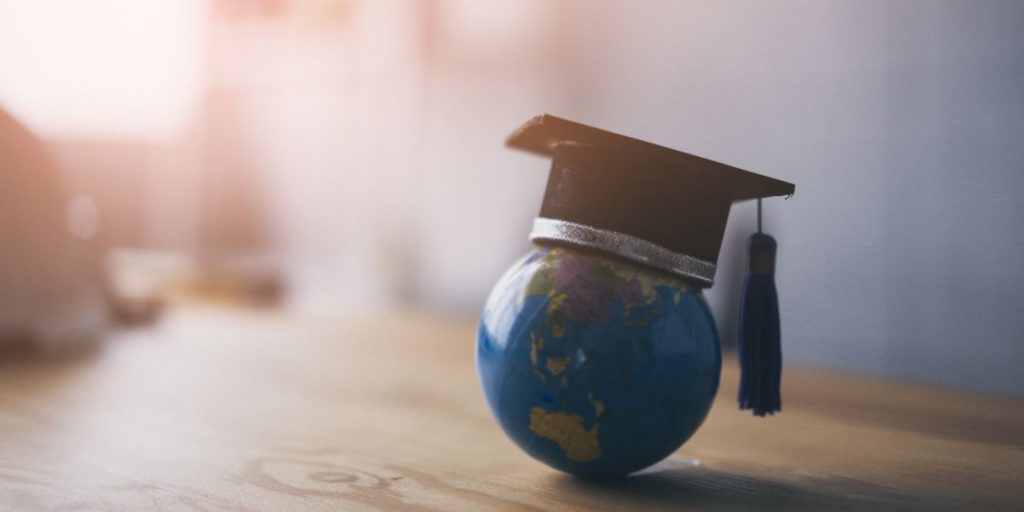 tiny globe on a desk with graduation cap