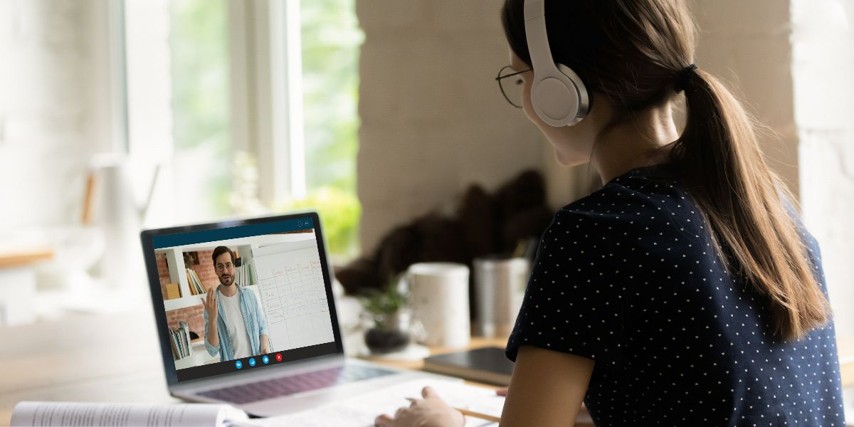 female student sitting at laptop at home with headphones listening to lecture