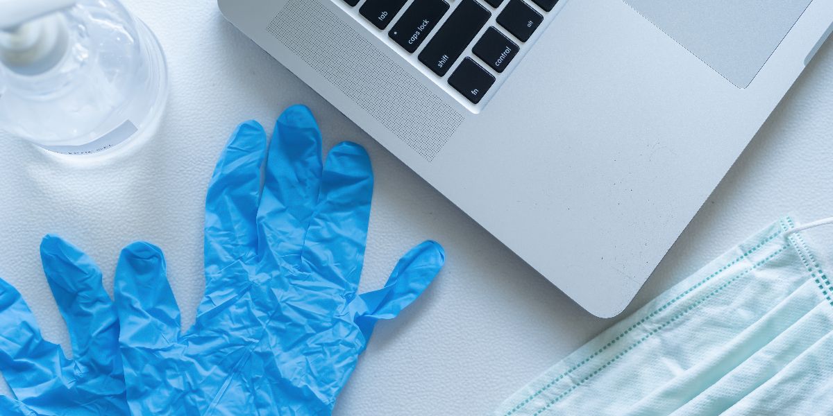 aerial view of laptop, gloves, mask, and hand sanitizer