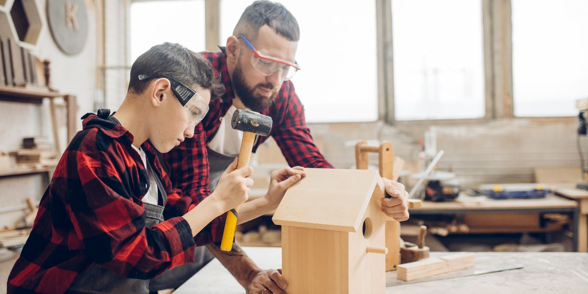 man and son work in woodshop to build birdhouse