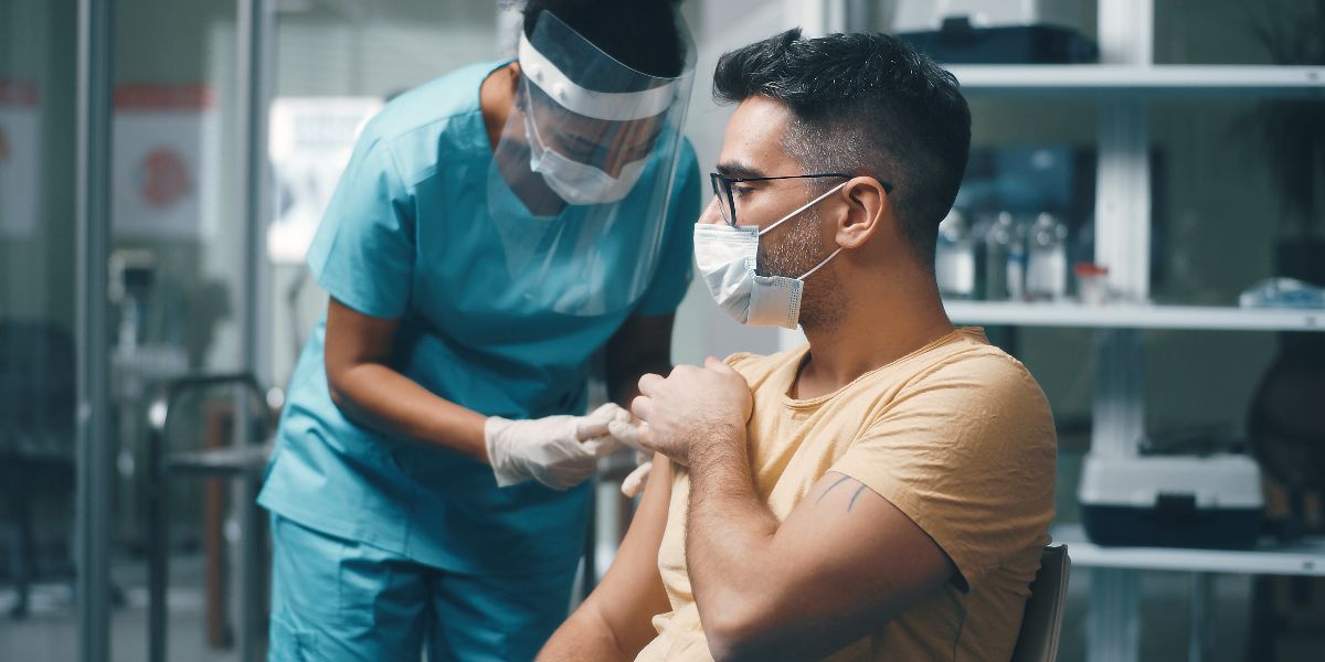 man with face mask getting vaccine from nurse with mask and face shield