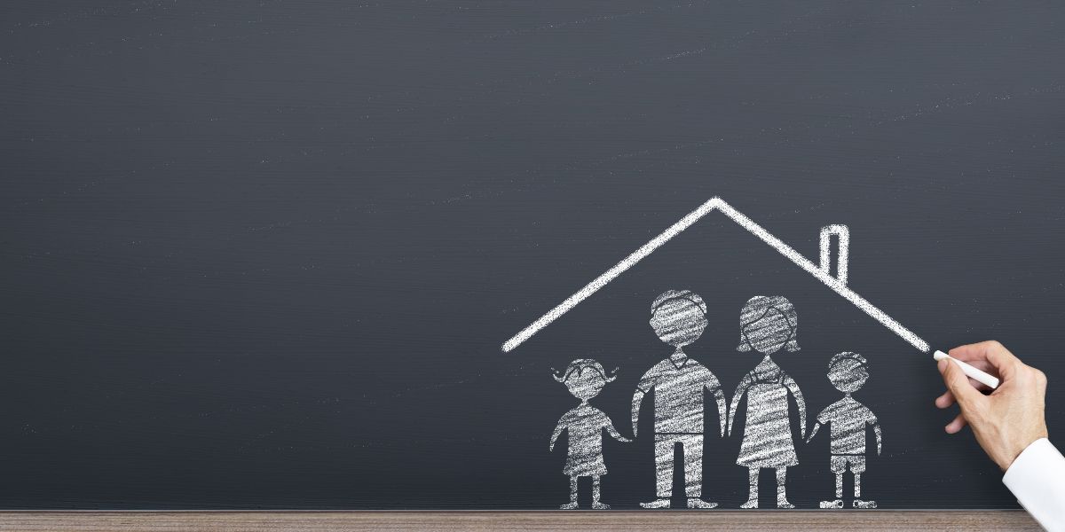 hand with chalk drawing family and house on chalkboard