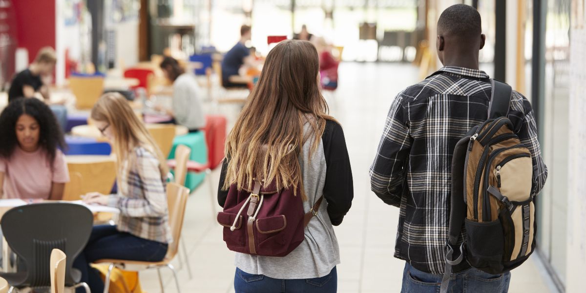 two students walking away from camera through a campus common area