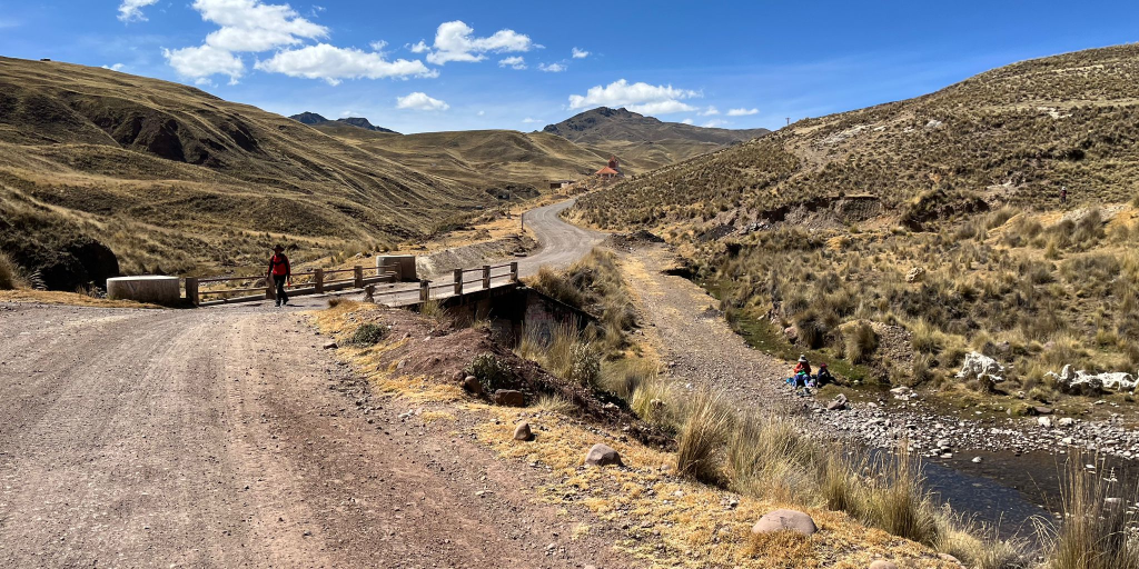 photo showing a person crossing a bridge on a remote roadway in Peru