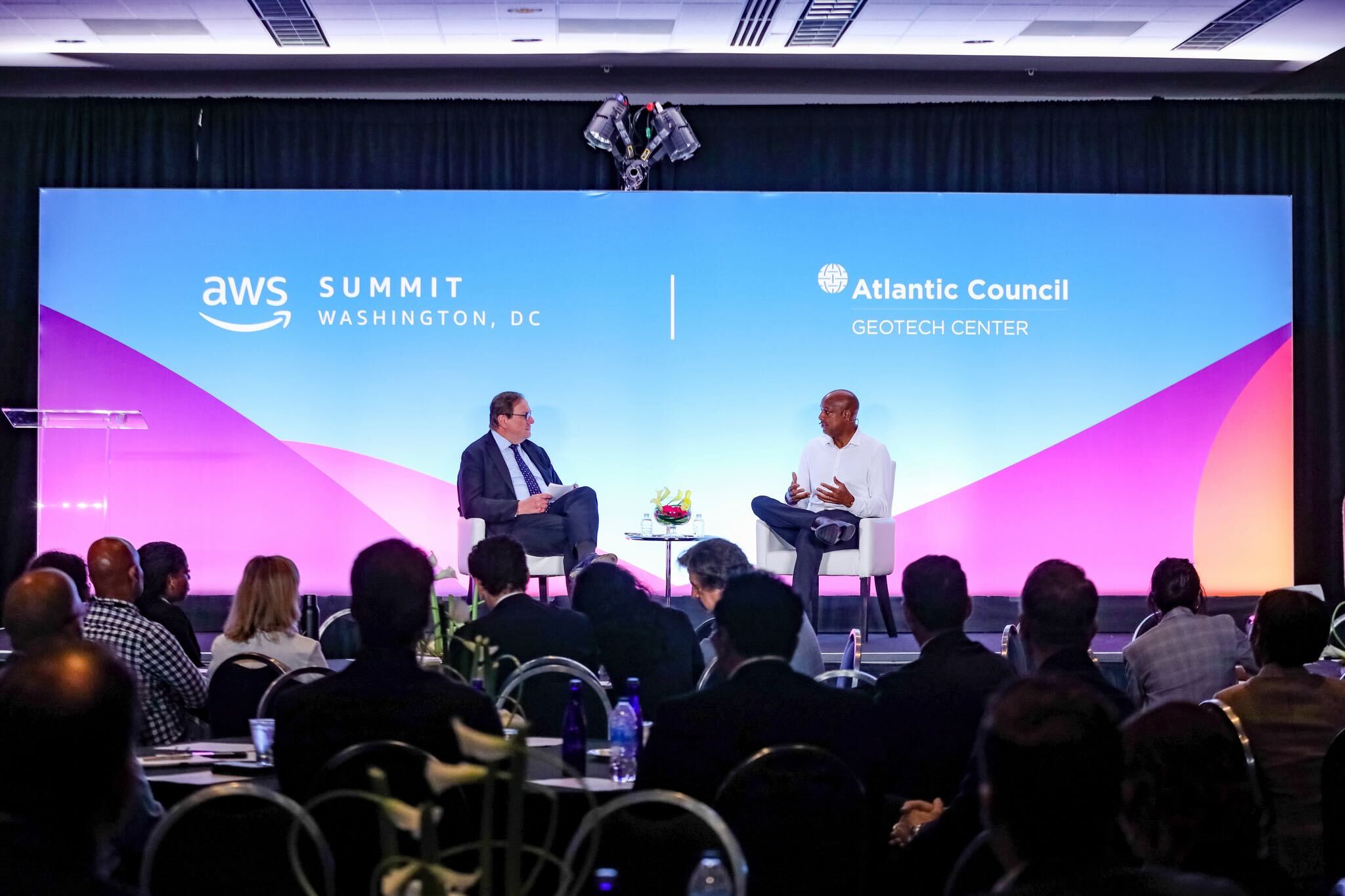 photo shows an audience watching Dave Levy seated on stage with a moderator at the event