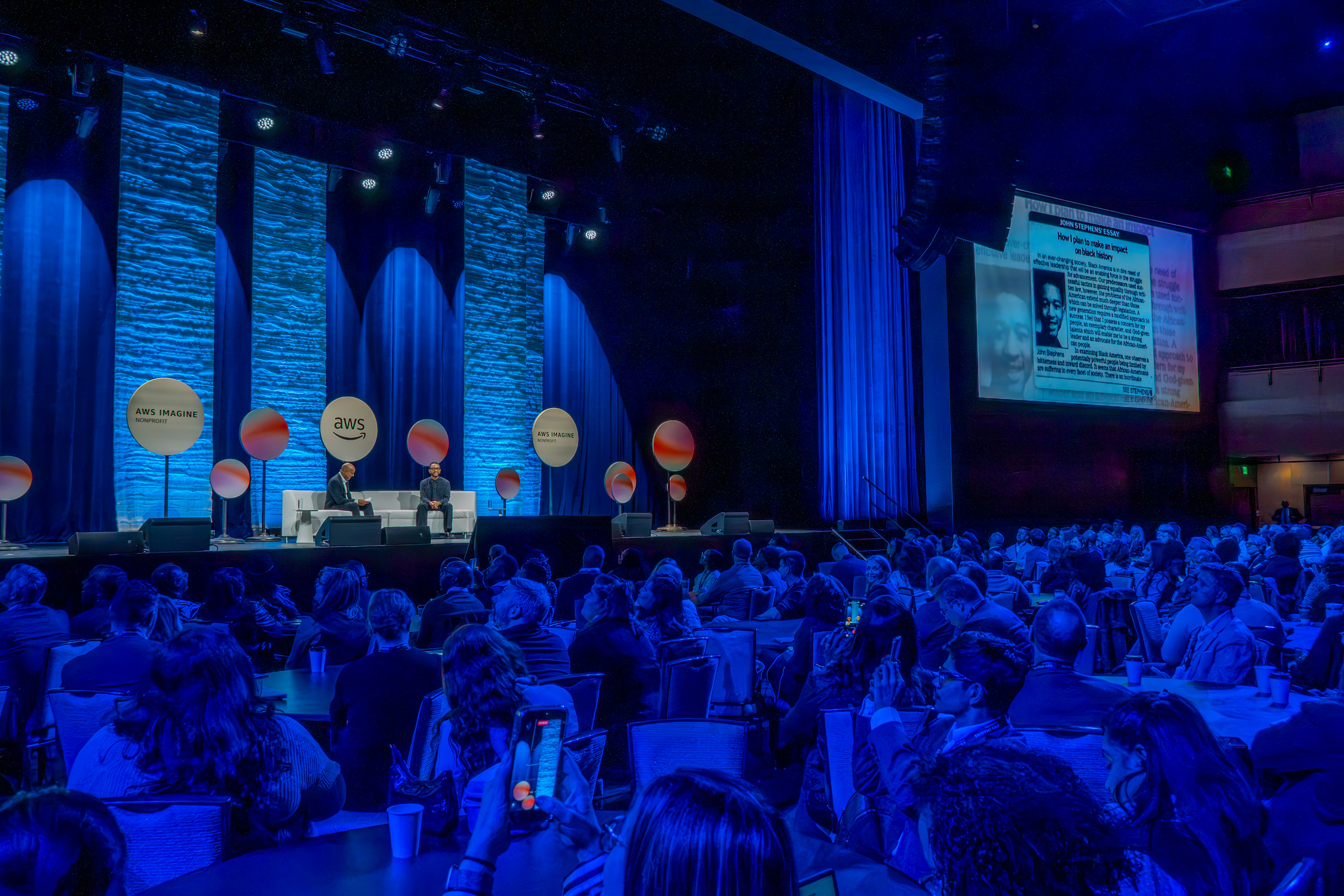event photo of crowd and stage with two speakers