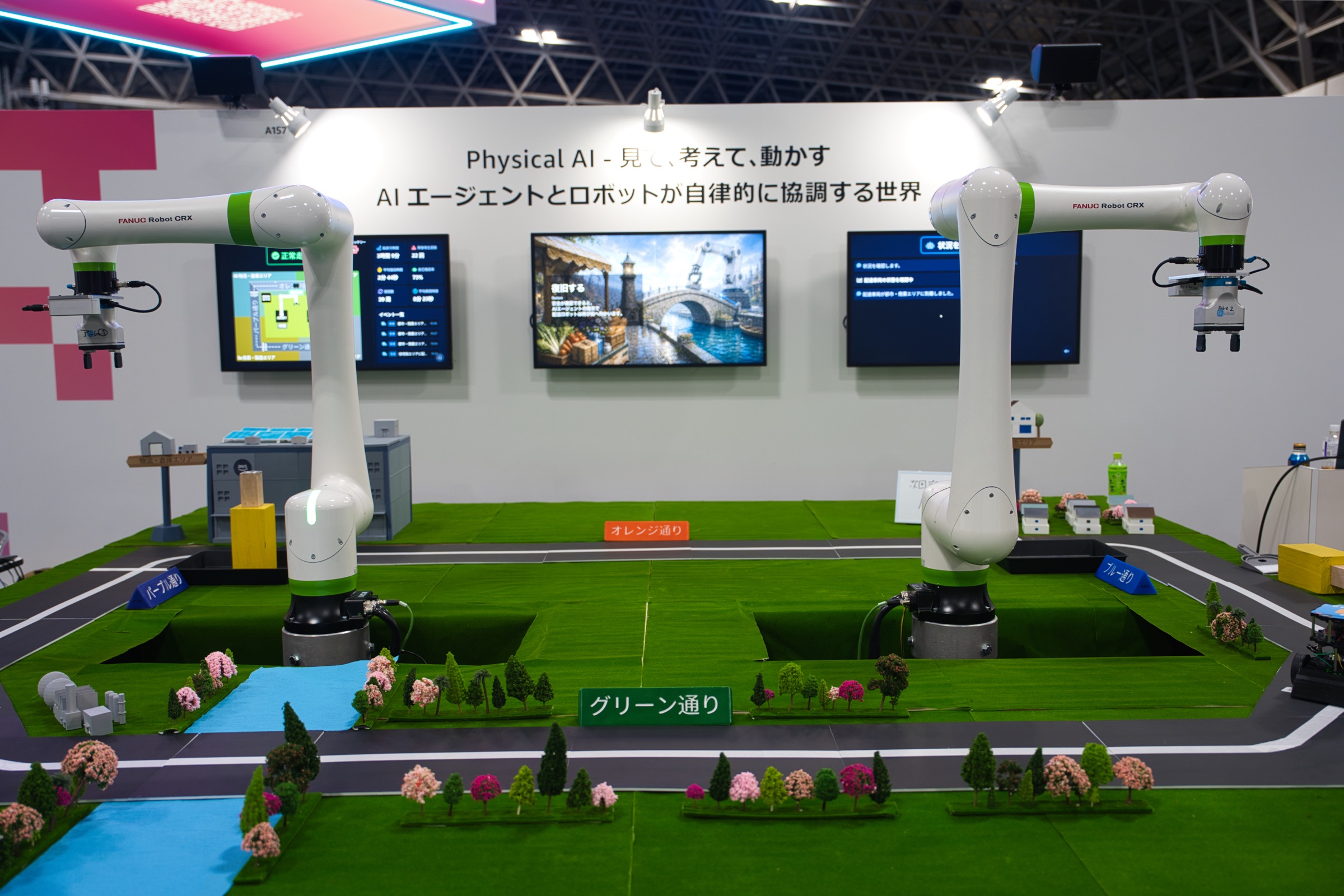 展示フィールドの左右に置かれた 2 台の協働ロボットと、中央の配送車両用周回路。