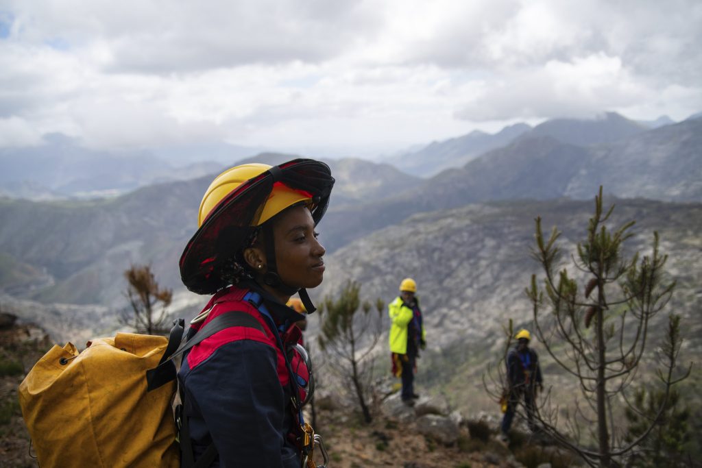 Image of person in mountains with yellow backpack and yellow hat