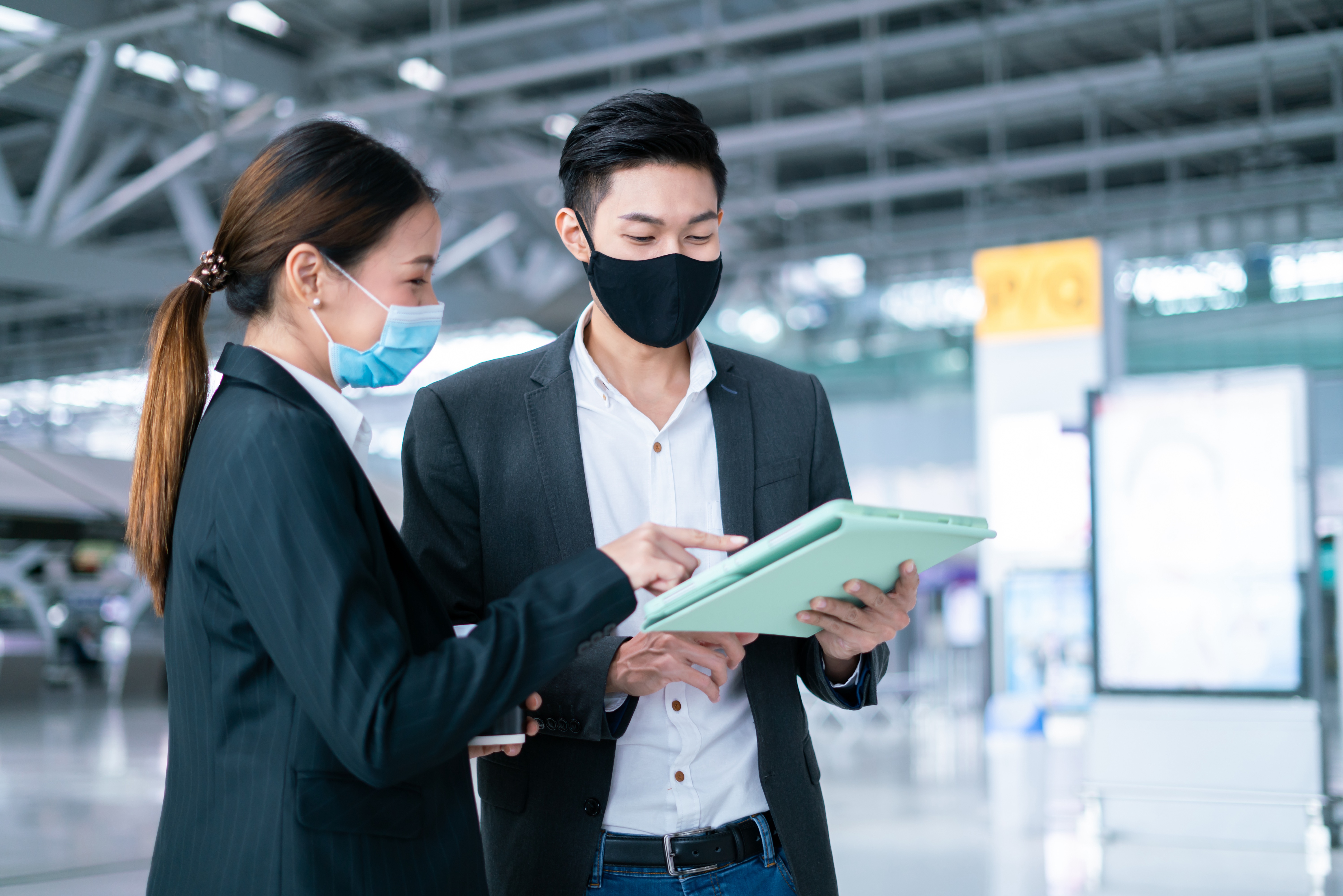 Businessman and businesswoman wearing face mask meeting during airline flight status