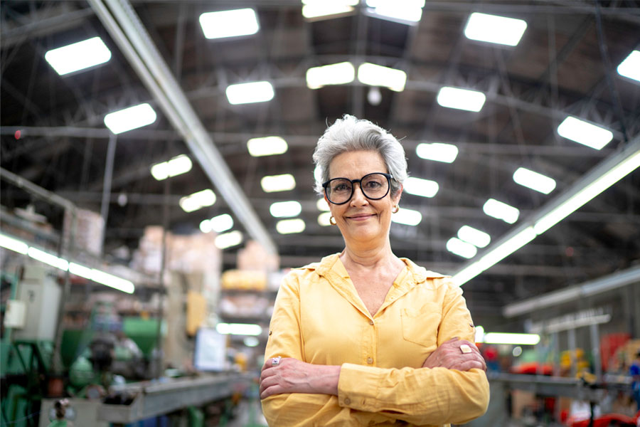 Woman standing in large manufacturing plant near machinery