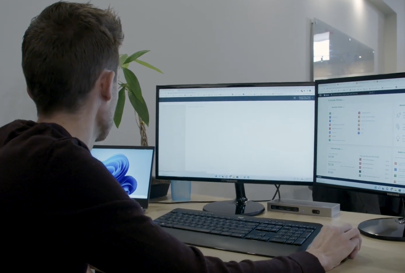 Man looking at three computer monitors with technical information