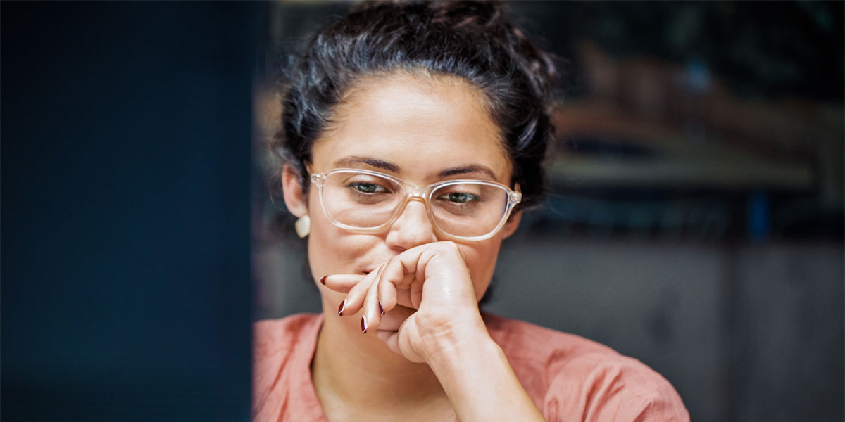 Woman staring at computer monitor pensively