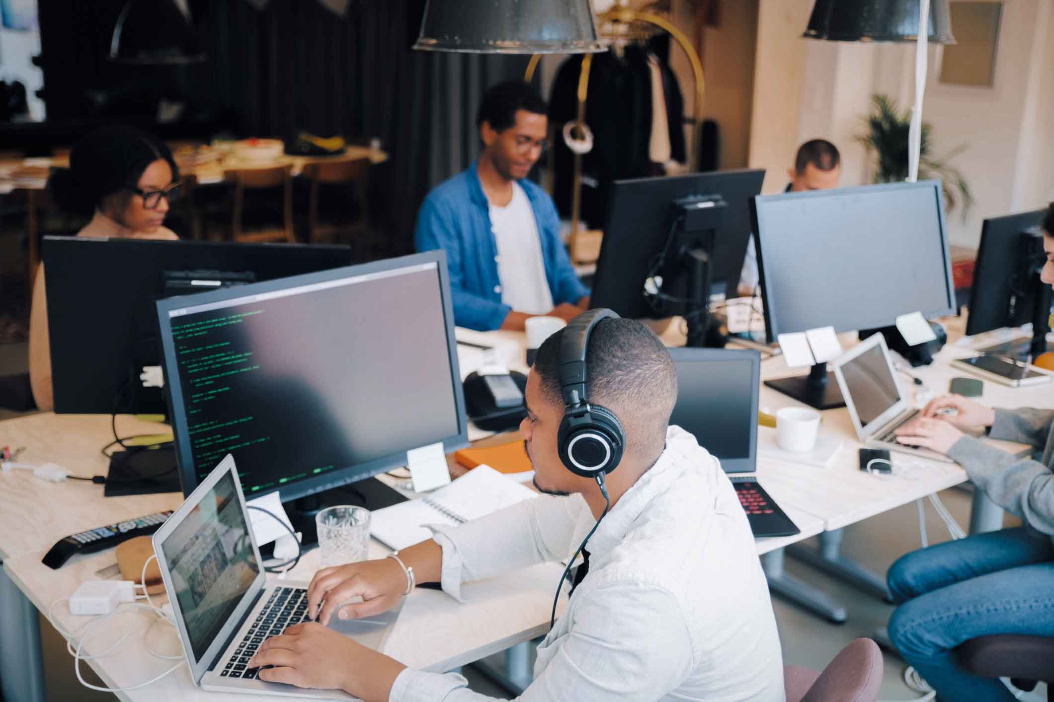 SMBs employees working together in an office at a long table in front of computer monitors