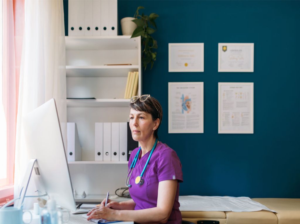 Healthcare provider adding patient data to her desktop computer in an office setting.