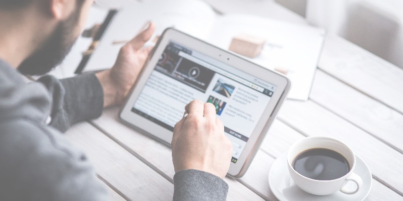 Man reads news on ipad to demonstrate how ivideosmart matches relevant videos to content for more effective advertising