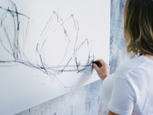 A female painter sketching a preparatory drawing with charcoal on canvas