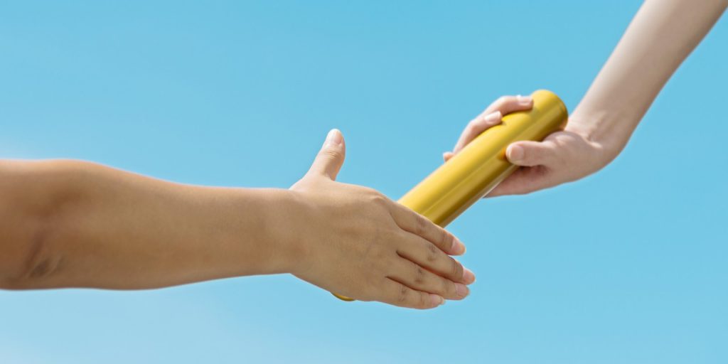 A close up of two people passing a baton