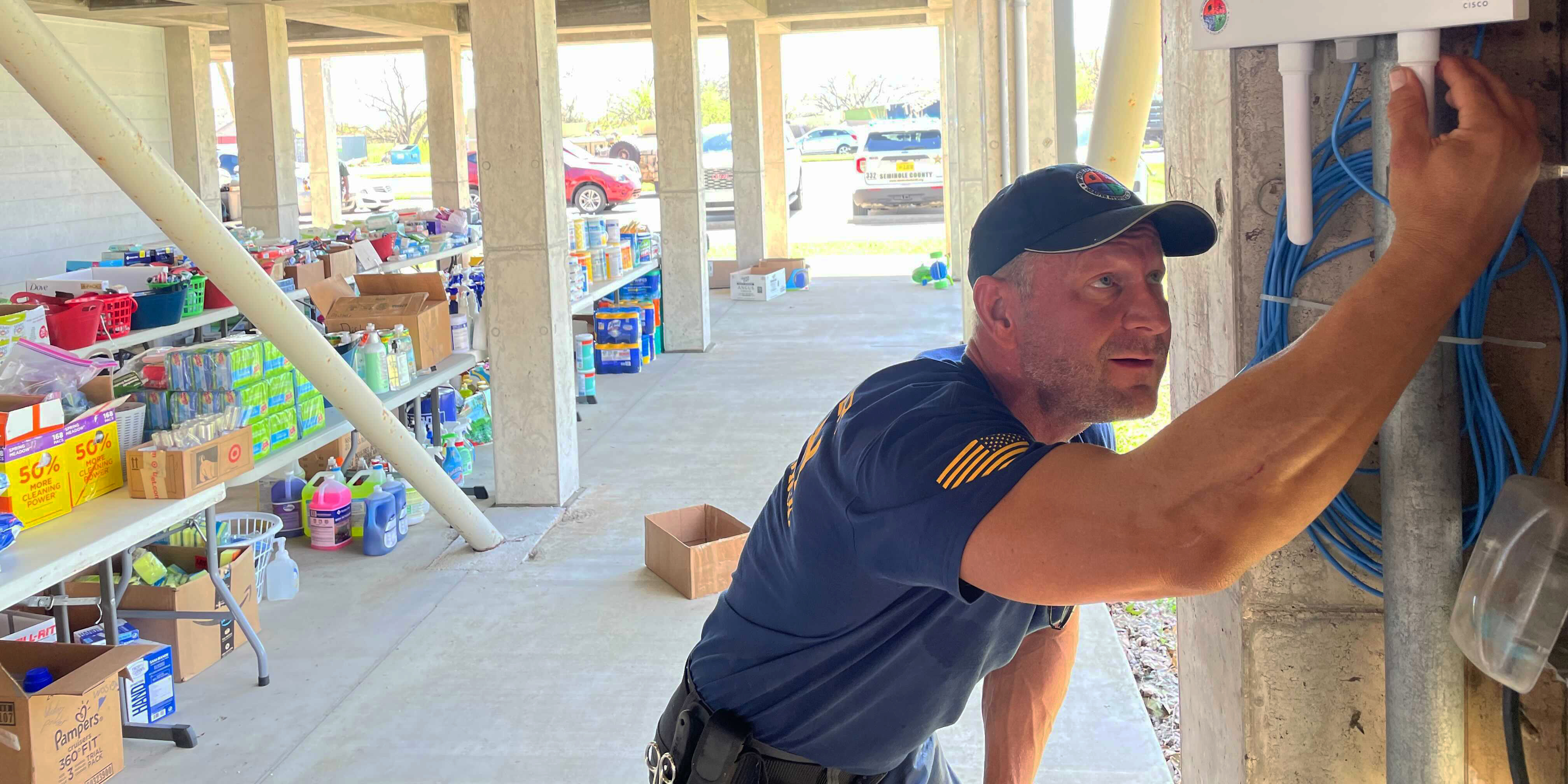 Image of a man in a blue shirt running cable through a wall.