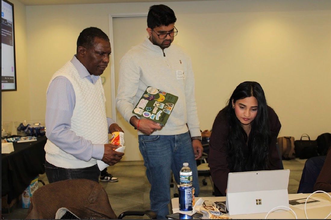 Three attendees looking at a laptop together while building a workflow during the workshop