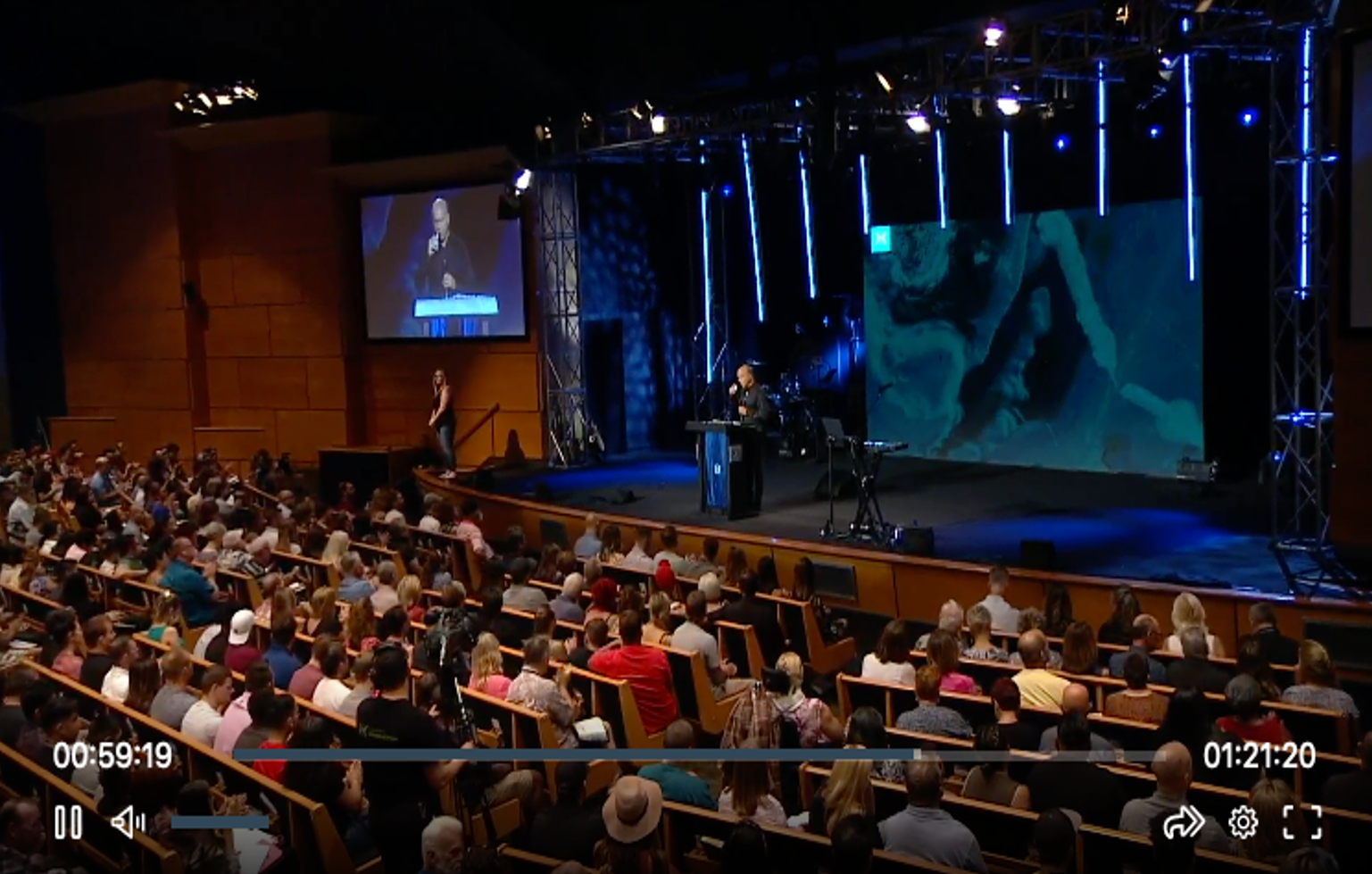 Screenshot of video broadcast from Harvest Christian Fellowship depicting a large audience enjoying a religious service.