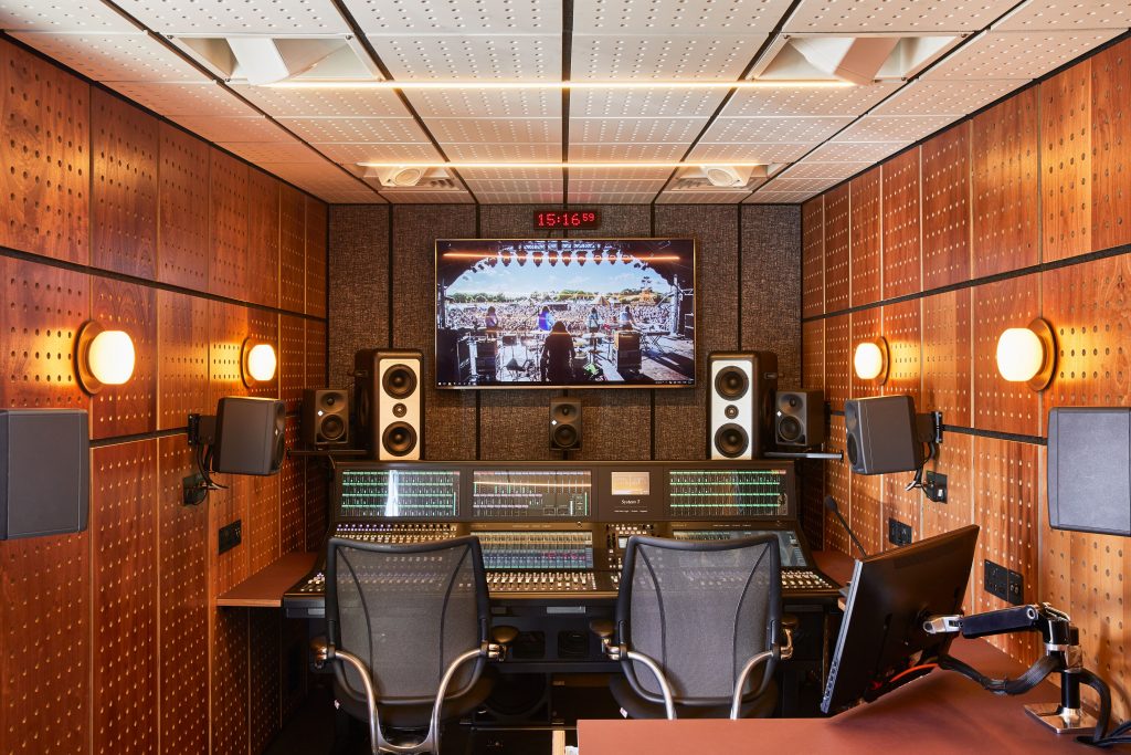 Inside of the Spiritland production truck. On the far wall is a monitor, digital clock, multiple speakers and the soundboard. The sides of the truck are pegboard.