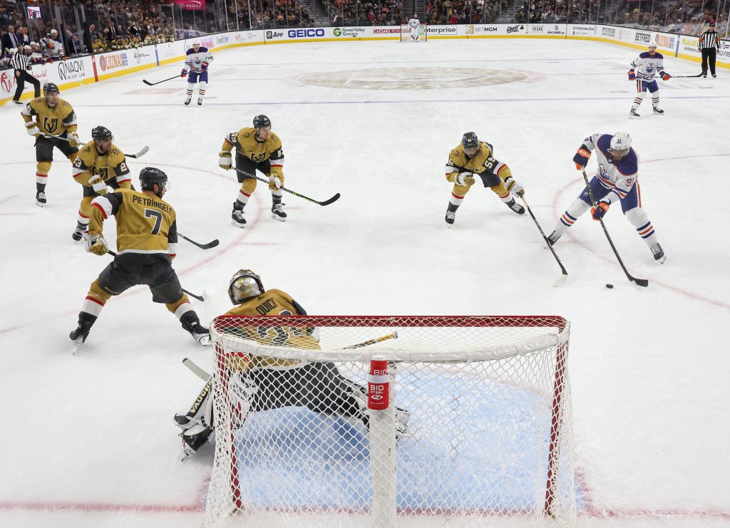 Hockey players on ice engaging with the goalie.