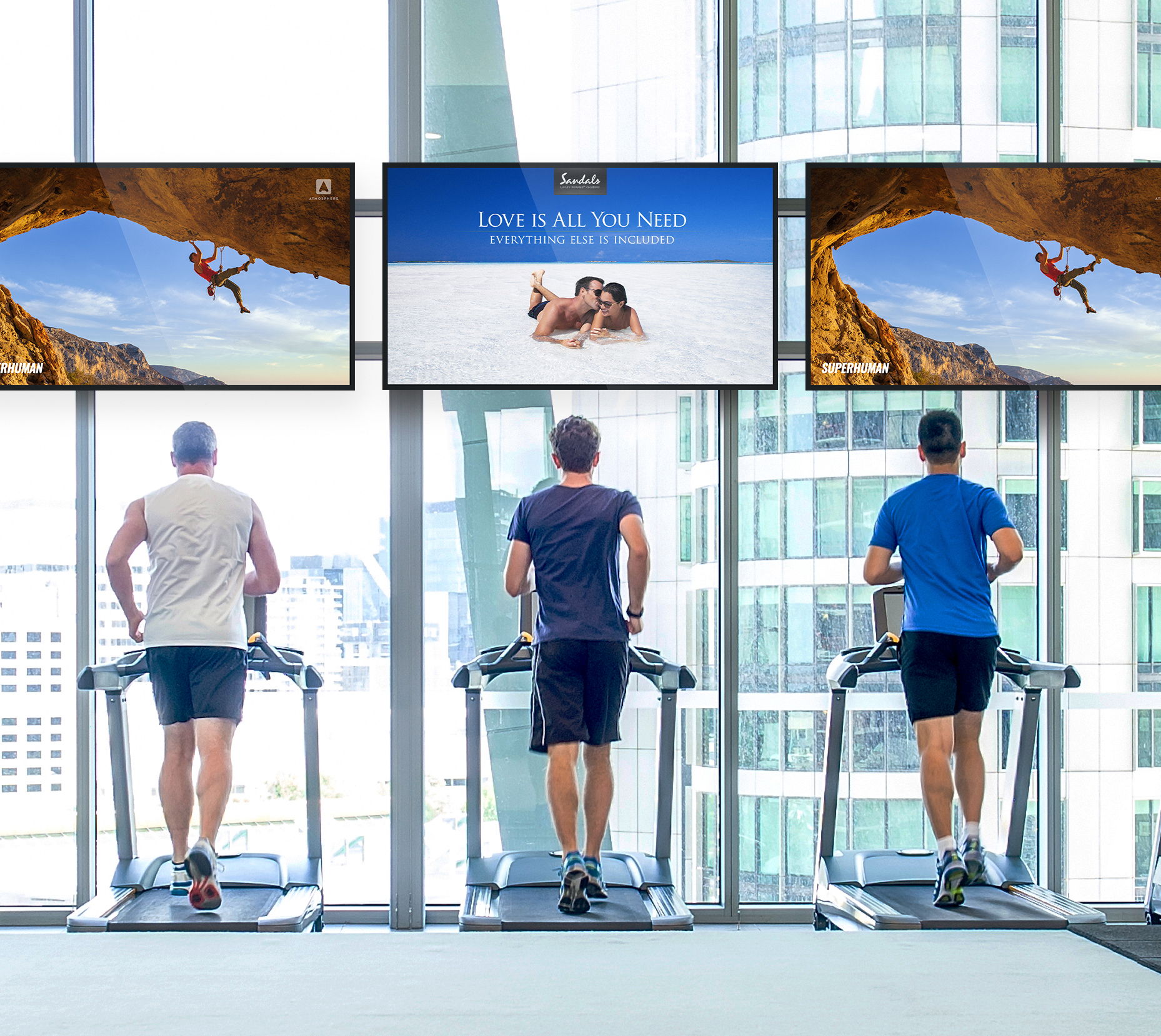 Three men on treadmills watching overhead televisions.